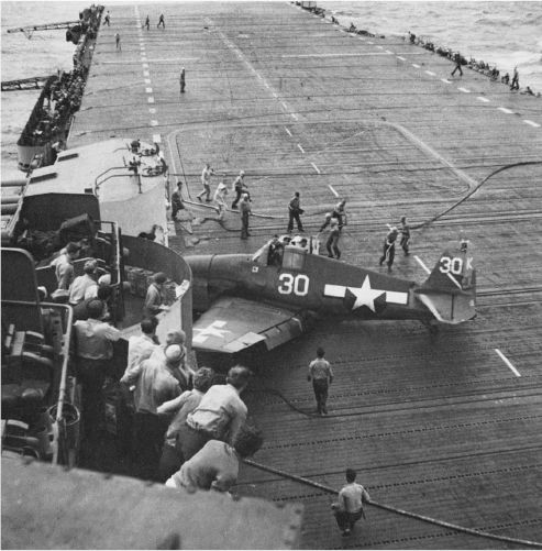 This VF-1 F6F returned to the Yorktown despite damage to oil and hydraulic systems and slight wounds to the pilot. Plane handlers rush to help the “Top Hat” flier from his aircraft.